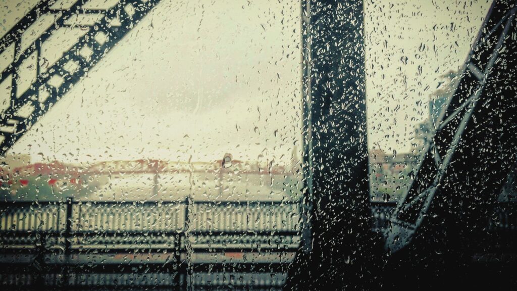 A gray, rainy view of Portland's Willamette River and Broadway Bridge from a train on the Steel Bridge